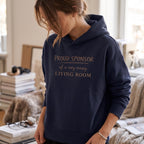 Woman wearing Kiksy dark blue hoodie featuring the text Proud Sponsor of a very messy LIVING ROOM