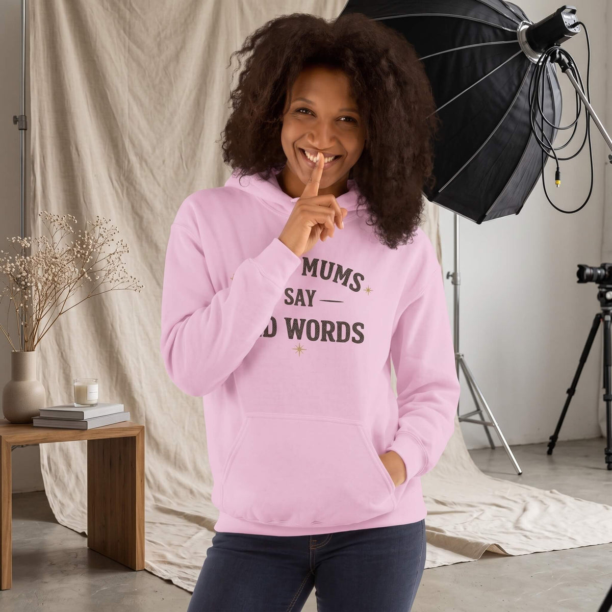 Kiksy light pink hoodie with Good Mums Say Bad Words printed on the front worn by a smiling woman